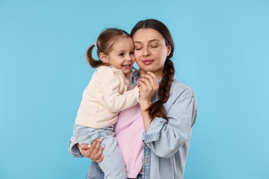 Photo of Portrait of happy mother with her cute daughter on light blue background