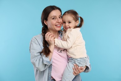 Photo of Portrait of happy mother with her cute daughter on light blue background