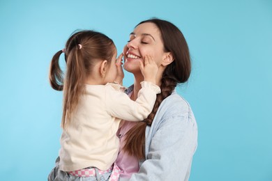 Photo of Happy mother with her cute daughter on light blue background