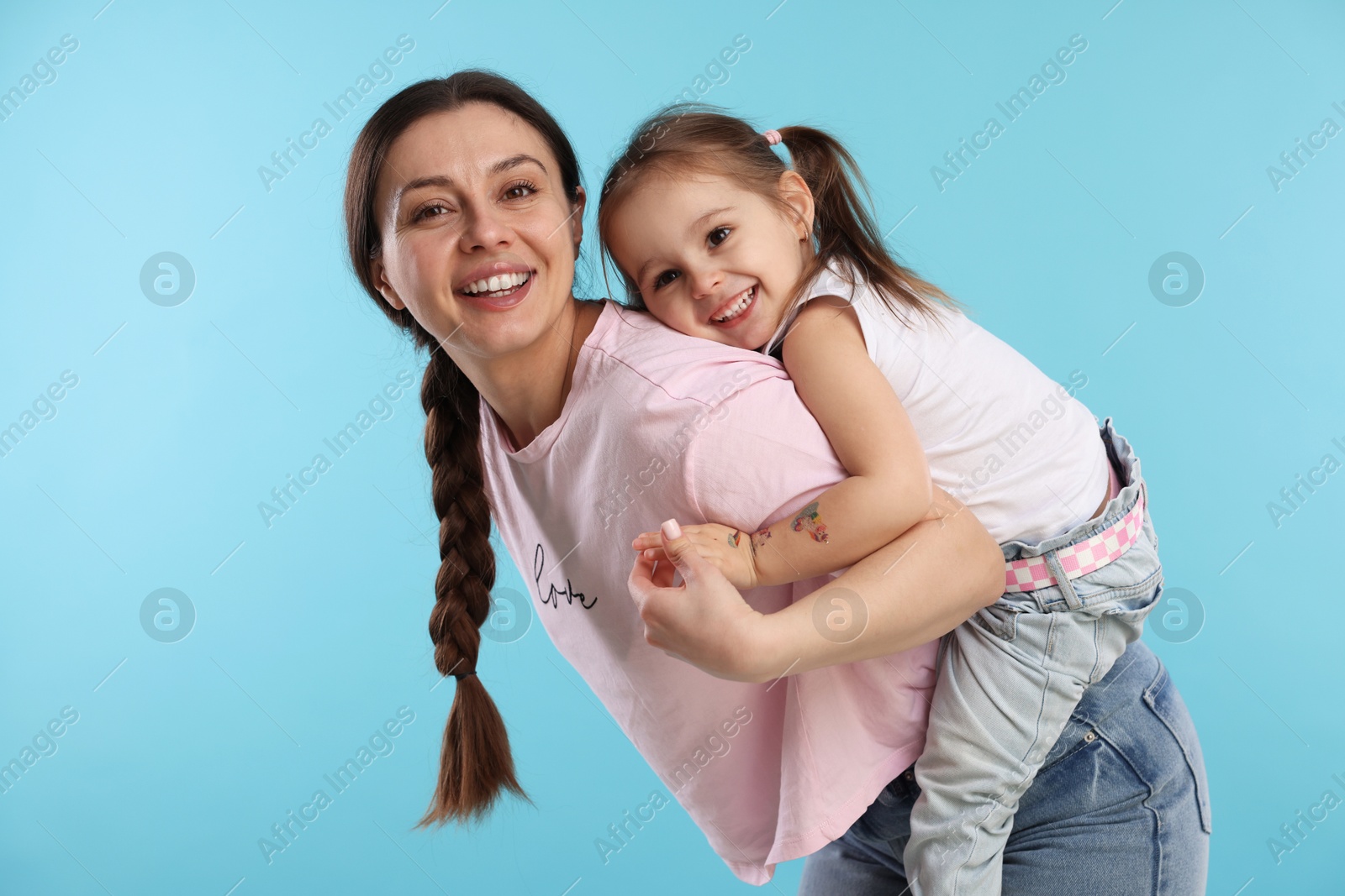 Photo of Portrait of happy mother with her cute daughter on light blue background