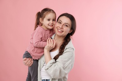 Portrait of happy mother with her cute daughter on pink background