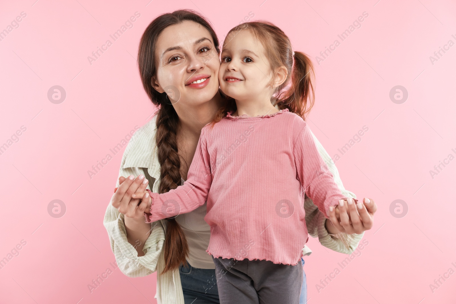 Photo of Family portrait of beautiful mother with little daughter on pink background