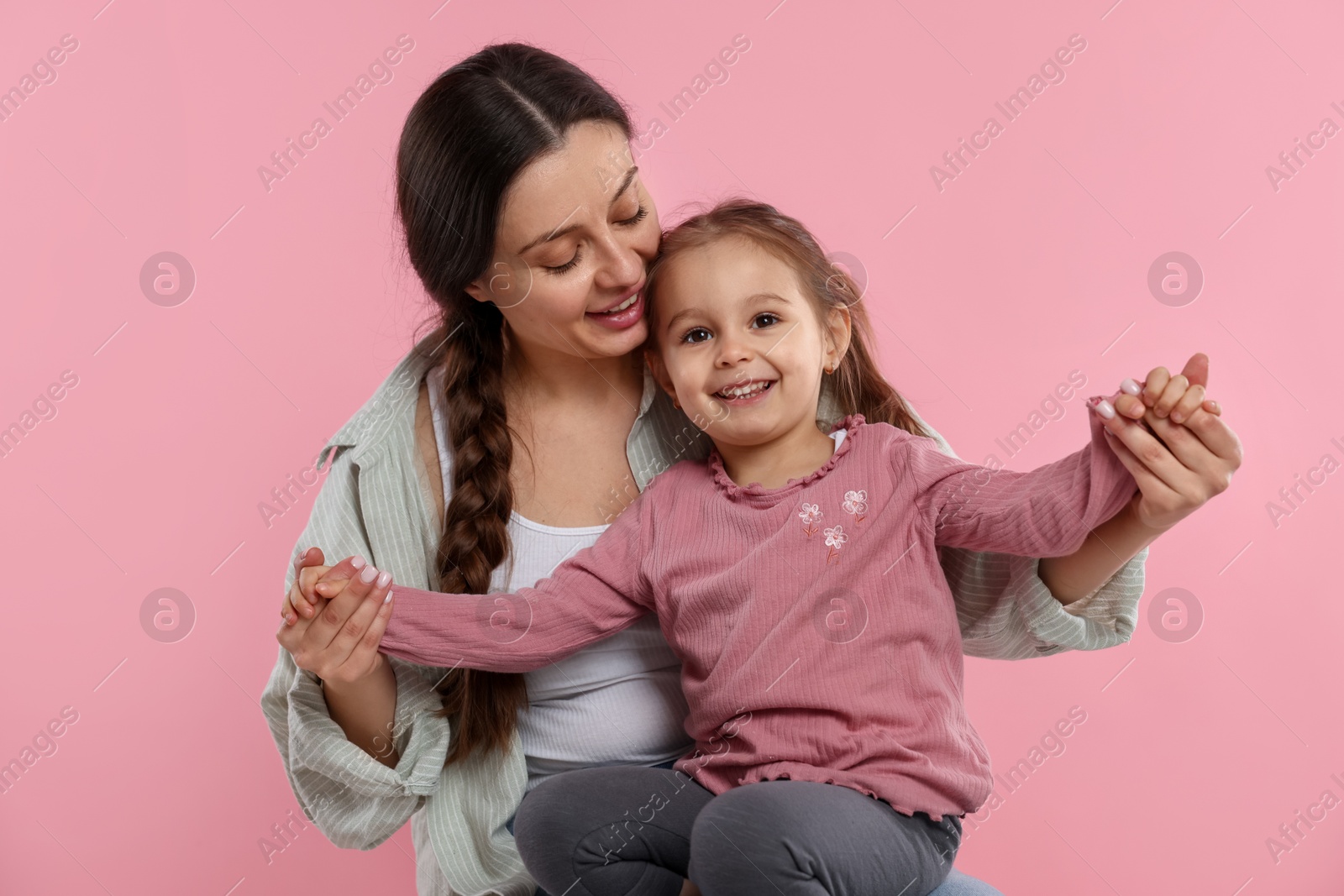 Photo of Family portrait of beautiful mother with little daughter on pink background