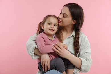 Portrait of mother with her cute daughter on pink background