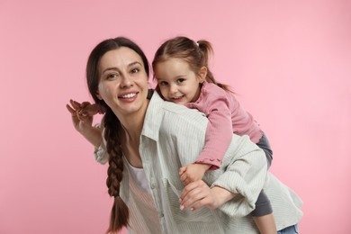 Photo of Portrait of happy mother and her cute daughter on pink background