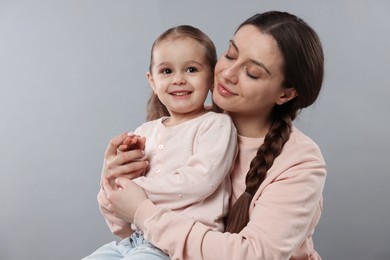 Family portrait of beautiful mother with little daughter on grey background