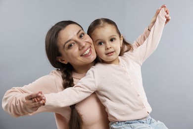 Photo of Family portrait of beautiful mother with little daughter on grey background