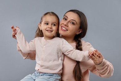 Family portrait of beautiful mother with little daughter on grey background