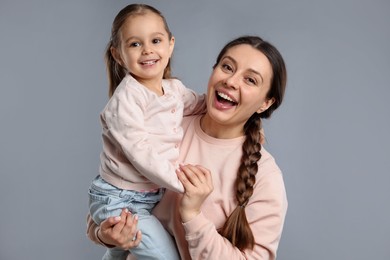 Family portrait of happy mother with little daughter on grey background