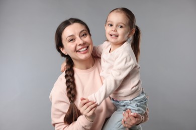 Photo of Family portrait of happy mother with little daughter on grey background