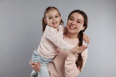 Photo of Family portrait of happy mother with little daughter on grey background