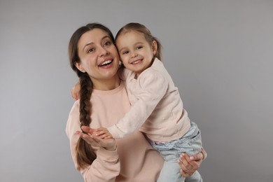 Photo of Family portrait of happy mother with little daughter on grey background