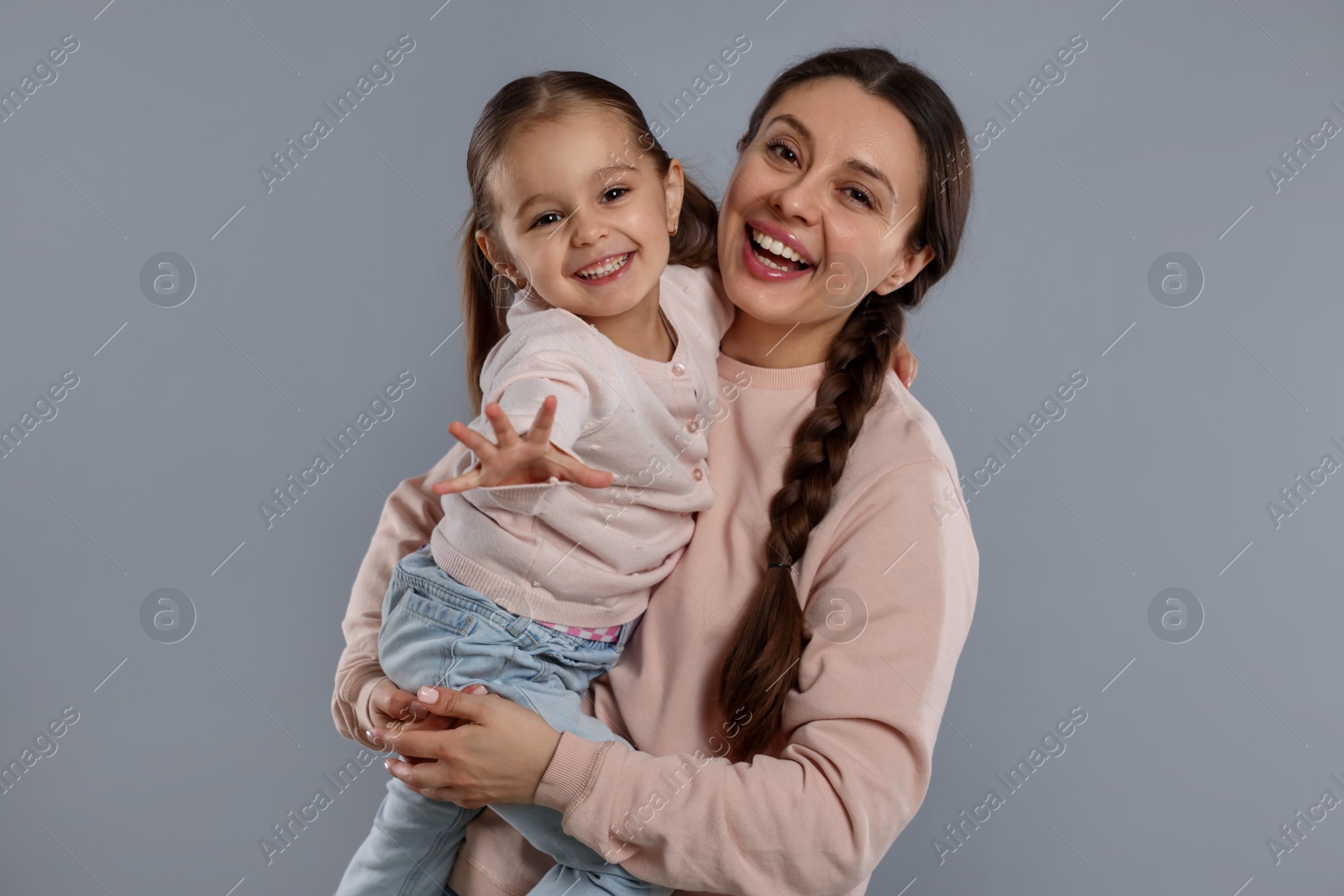 Photo of Family portrait of happy mother with little daughter on grey background