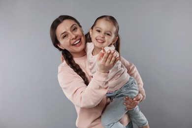 Family portrait of happy mother with little daughter on grey background