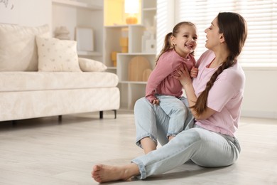 Happy mother with her little daughter spending time together at home. Space for text