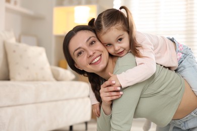 Family portrait of happy mother with her little daughter at home. Space for text