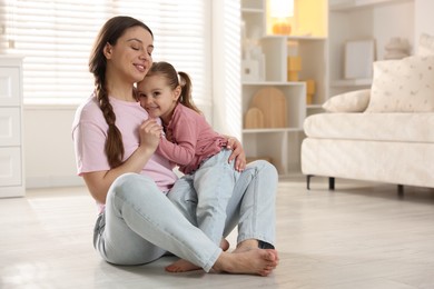 Happy mother with her little daughter spending time together at home. Space for text