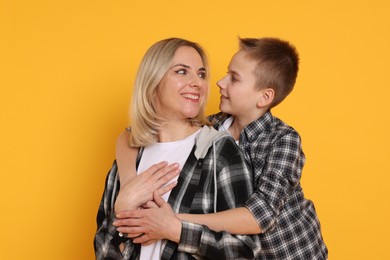 Photo of Mother and son hugging on orange background