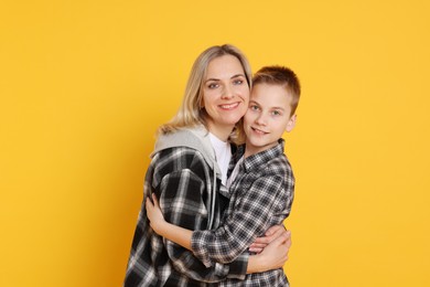 Photo of Mother and son hugging on orange background