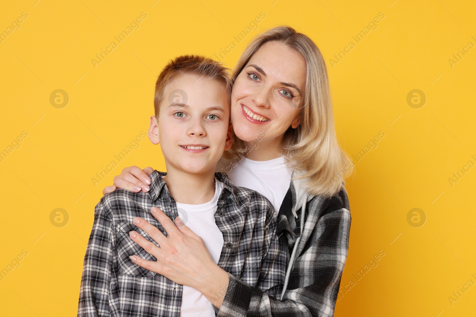 Photo of Mother and son hugging on orange background