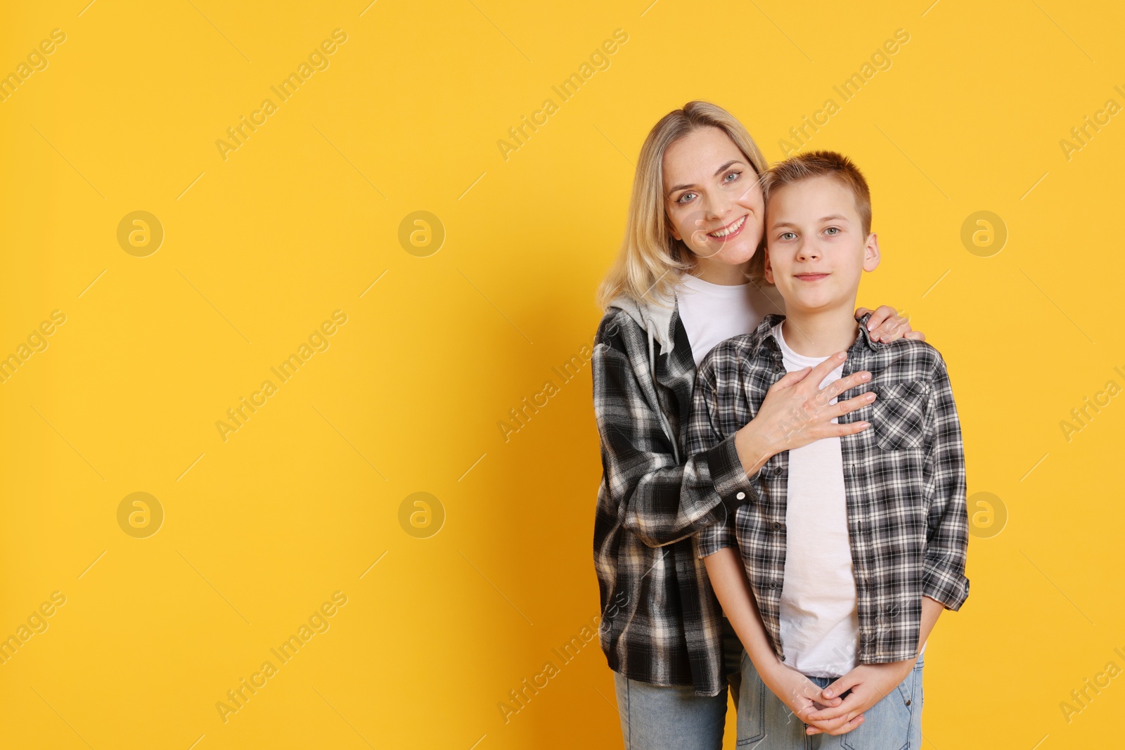 Photo of Happy mother and son on orange background. Space for text