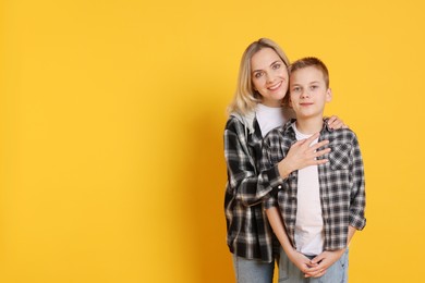 Photo of Happy mother and son on orange background. Space for text