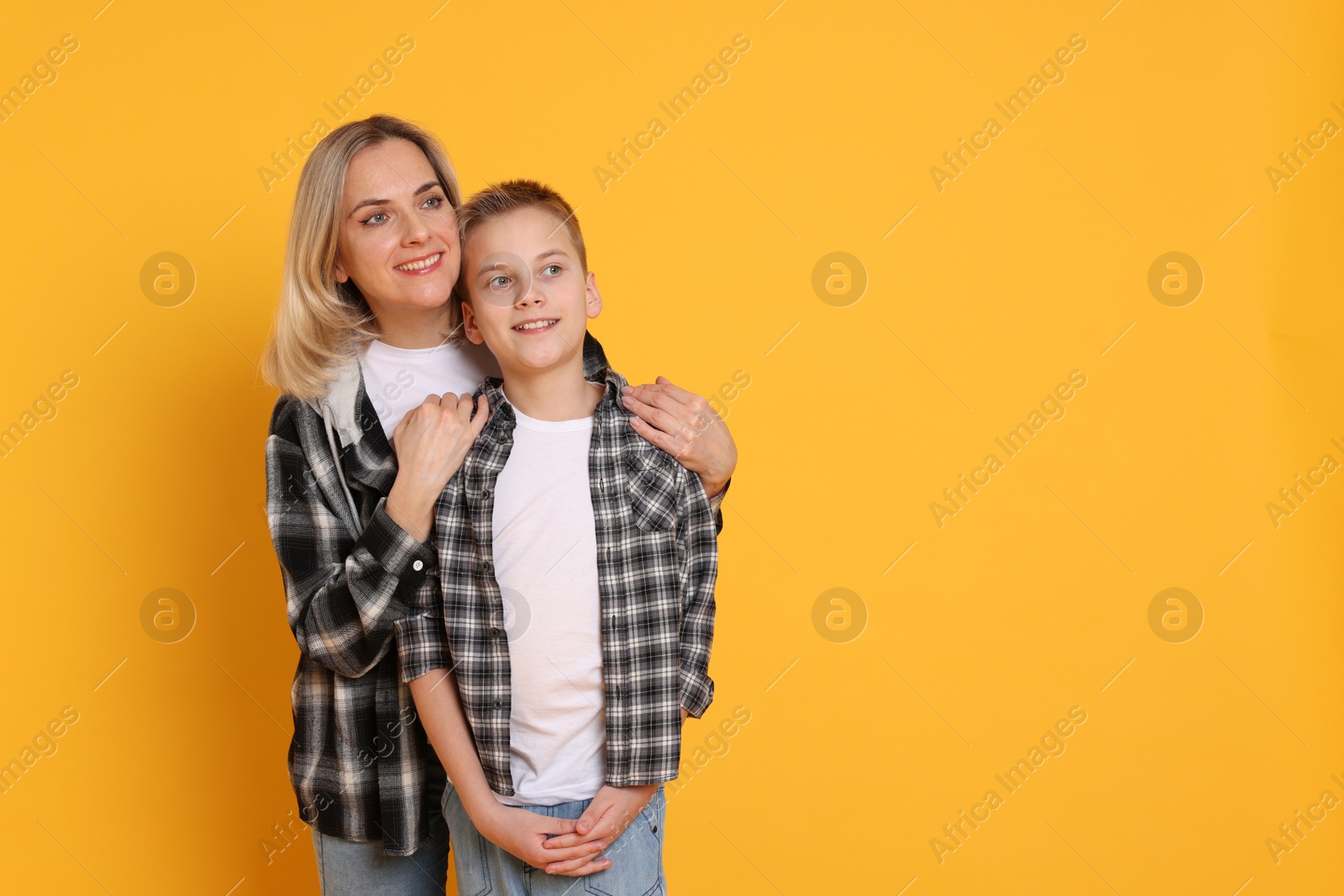 Photo of Happy mother and son on orange background. Space for text