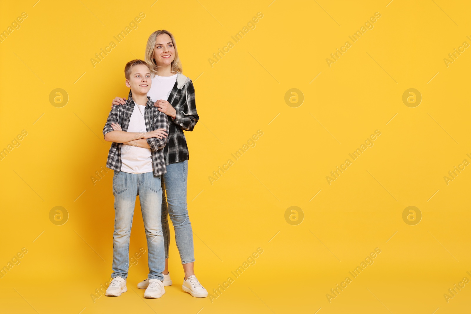 Photo of Happy mother and son on orange background. Space for text