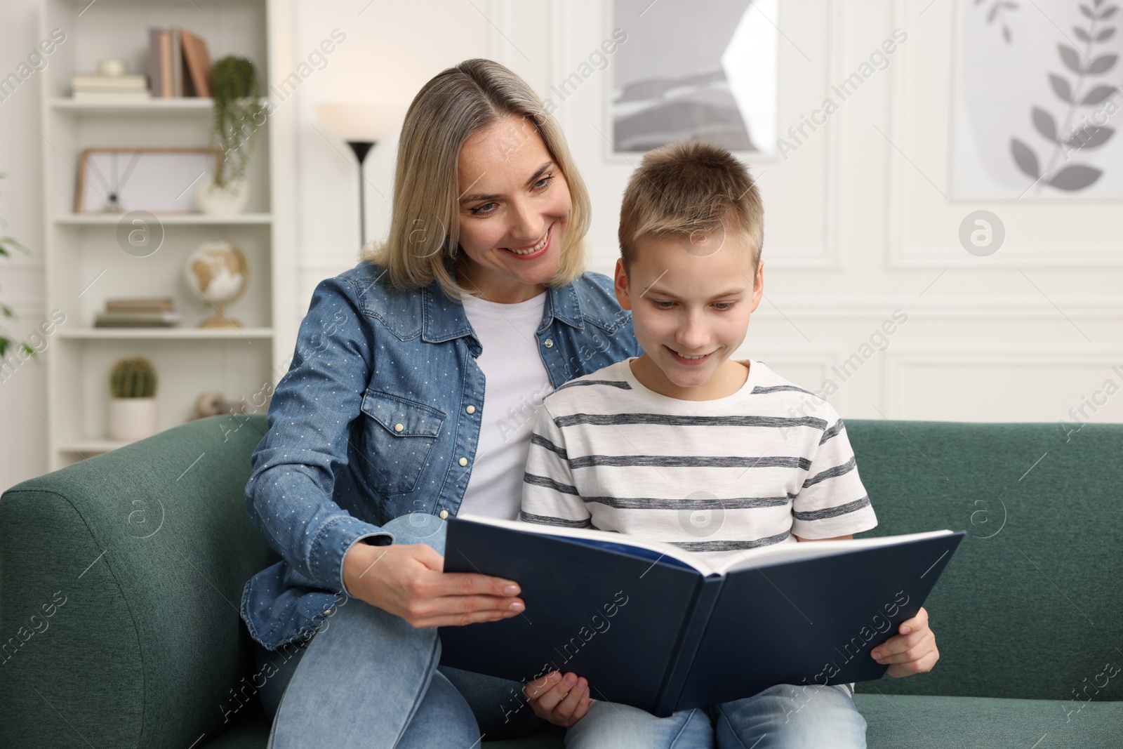 Photo of Mother and son reading book on sofa at home