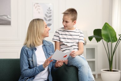 Photo of Son giving card to his mom at home