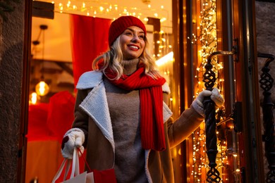 Photo of Happy woman with shopping bags near shop outdoors. Christmas season