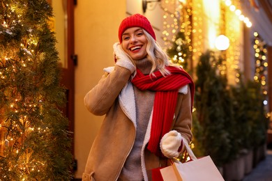 Photo of Happy woman with paper bag on city street. Christmas season