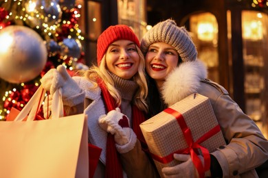 Happy friends with Christmas gift and shopping bags on city street