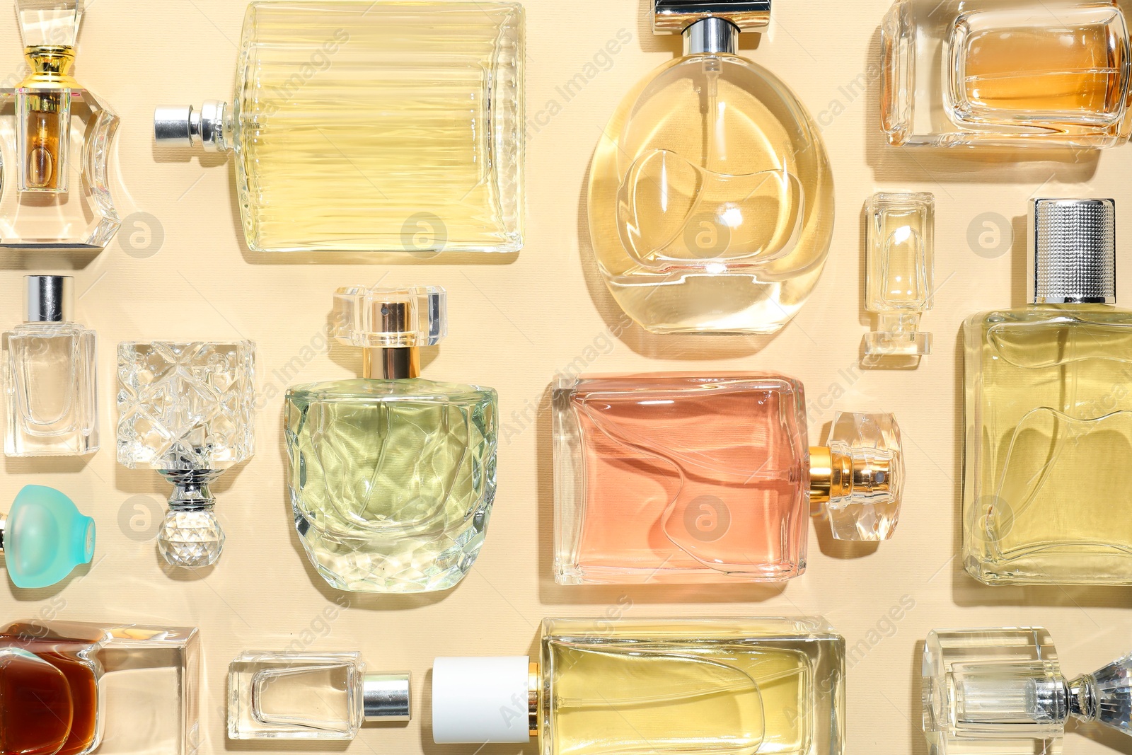 Bottles of various perfumes on beige background, flat lay Photo of Bottles of various perfumes on beige background, flat lay