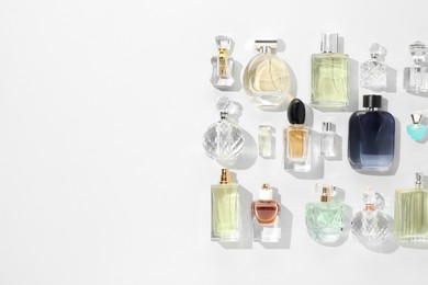 Photo of Bottles of various perfumes on white background, flat lay. Space for text