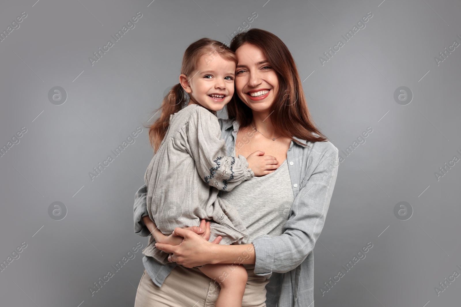 Photo of Portrait of happy mother with her cute little daughter on grey background