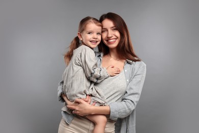 Photo of Portrait of happy mother with her cute little daughter on grey background