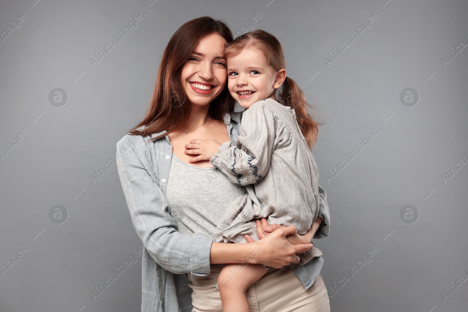 Photo of Portrait of happy mother with her cute little daughter on grey background