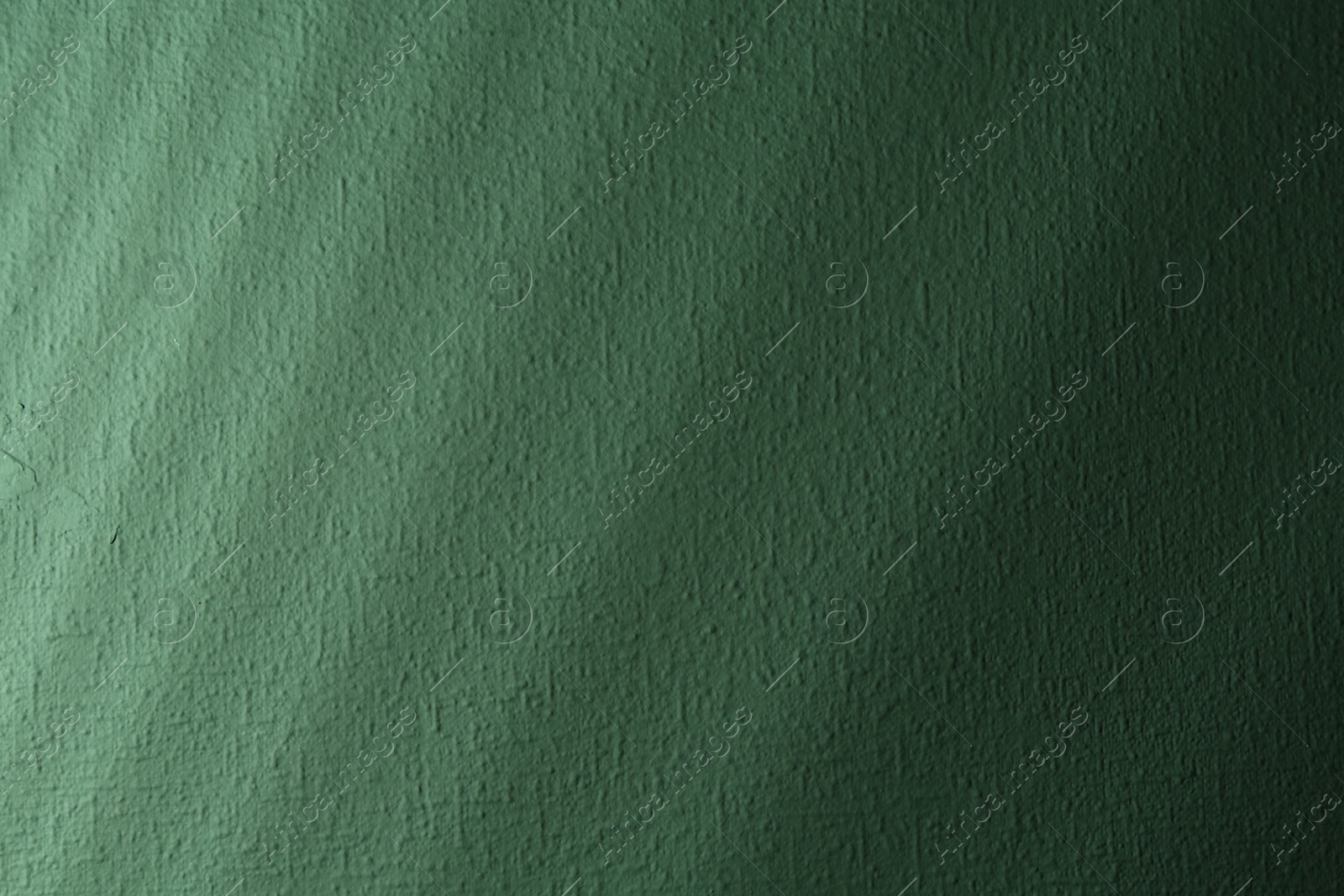 Photo of Light and shadows falling on green textured wall