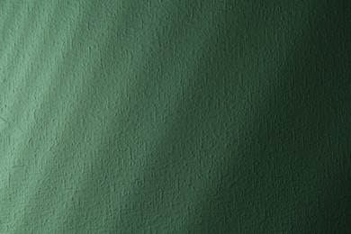 Photo of Light and shadows falling on green textured wall