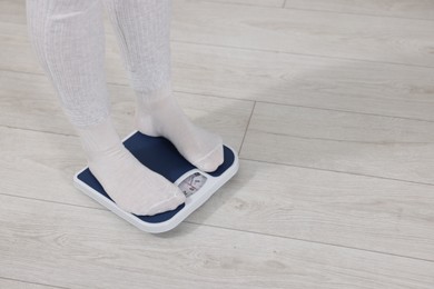 Photo of Woman on scales indoors, closeup with space for text. Weight loss