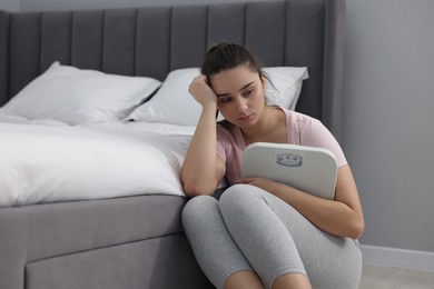 Photo of Depressed woman with scales on floor at home. Bulimia problem