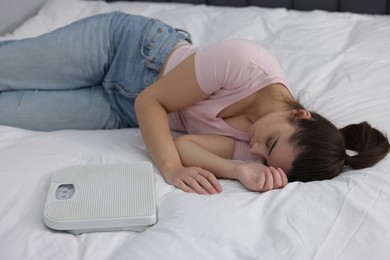 Photo of Depressed woman with scales on bed. Bulimia problem