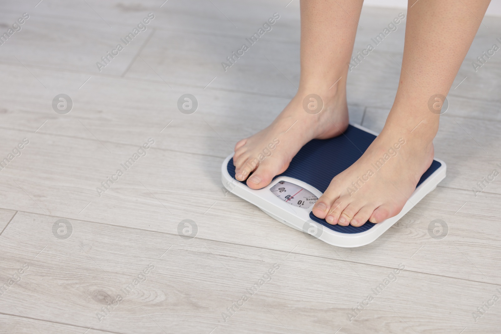 Photo of Woman on scales indoors, closeup with space for text. Weight loss