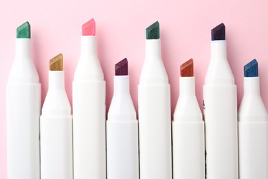 Colorful markers on pink background, flat lay