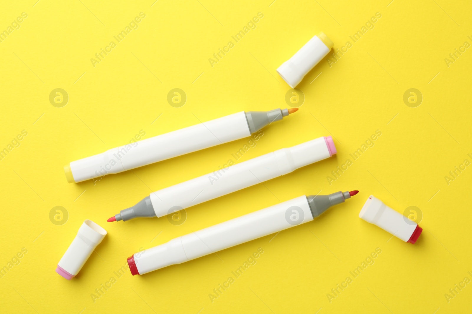 Photo of Colorful double sided markers on yellow background, flat lay