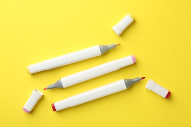 Colorful double sided markers on yellow background, flat lay