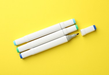 Photo of Colorful double sided markers on yellow background, flat lay