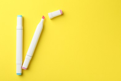 Photo of Two double sided markers on yellow background, flat lay. Space for text