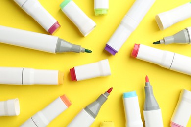 Colorful markers on yellow background, flat lay